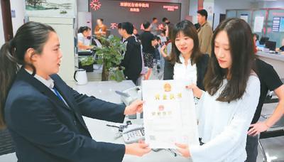 河北省承德市網(wǎng)絡(luò)代購經(jīng)營者陳晨(右)從工作人員手中接過帶有統(tǒng)一社會信用代碼的營業(yè)執(zhí)照。 劉環(huán)宇攝(人民圖片)