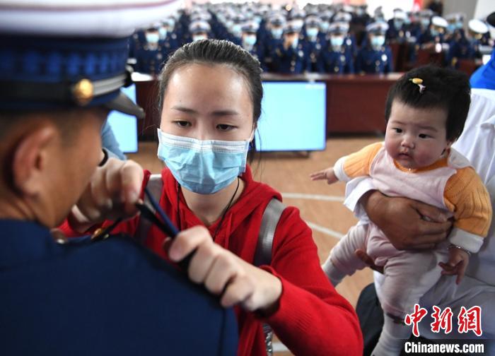 新消防員楊振的妻子彭莉與女兒現(xiàn)場見證丈夫加入“火焰藍”的神圣時刻?！⒅铱?攝