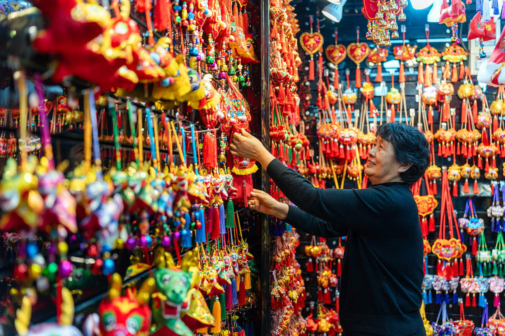 2023年12月11日，金華義烏國(guó)際商貿(mào)城，龍年喜慶用品掛滿(mǎn)攤位，顧客正在挑選中。
