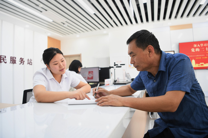 2023年5月23日，河北雄安新區(qū)容東片區(qū)南文營社區(qū)居民（右）在社區(qū)便民服務(wù)站辦理業(yè)務(wù)。